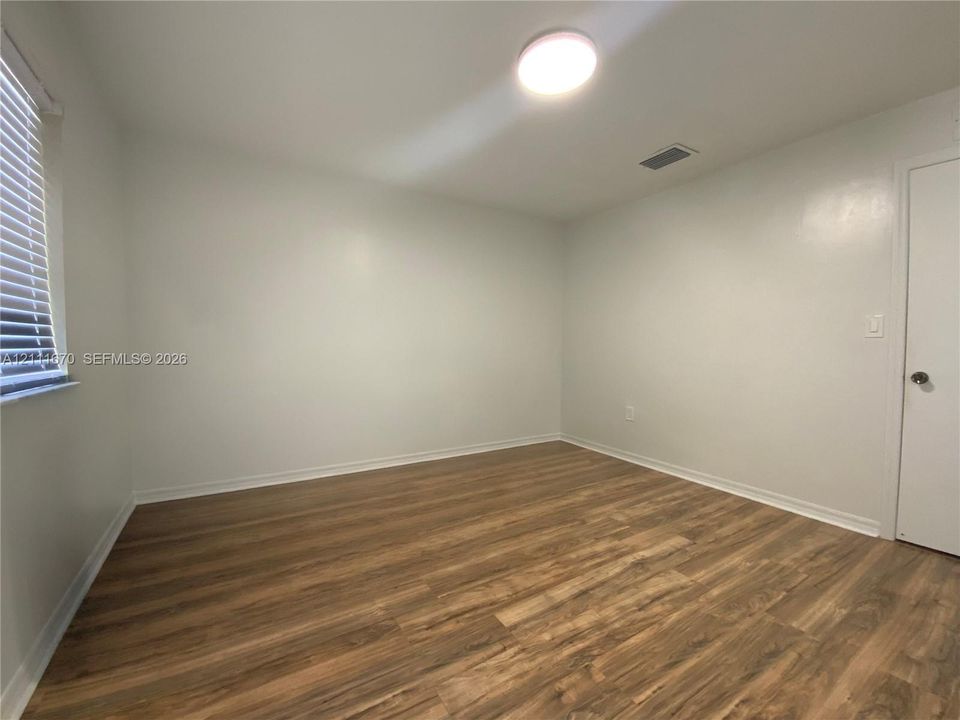 Neutral-Second Bedroom toned interior featuring wood-finish flooring, white walls, and a ceiling-mounted flush light fixture