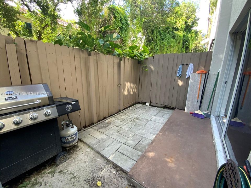 Enclosed patio featuring paved hardscaping and wood-style privacy fencing