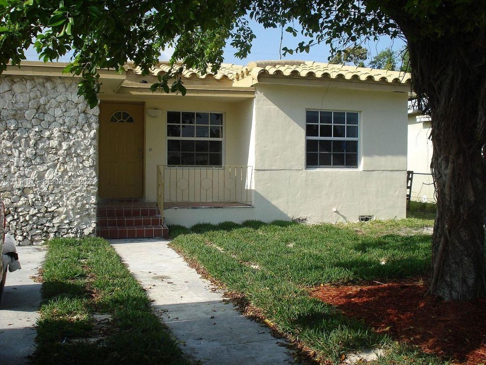 Exterior facade featuring a combination of natural stone veneer and smooth stucco finish, barrel tile roof, multi-pane windows, and a raised concrete porch with metal railing