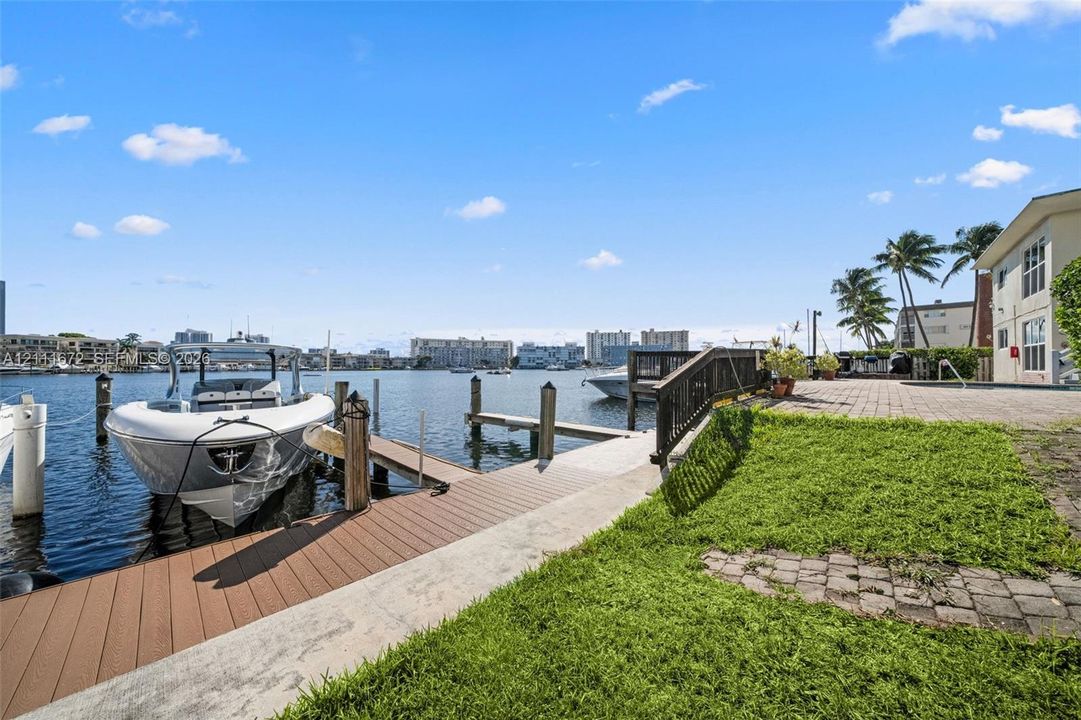 Waterfront property featuring a private boat dock, composite decking, paver patio, and lawn space
