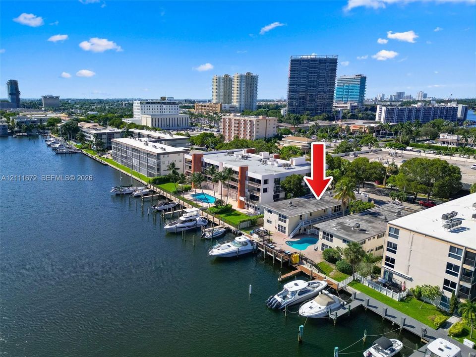 Waterfront property featuring a private boat dock, swimming pool, concrete bulkhead, and established tropical landscaping