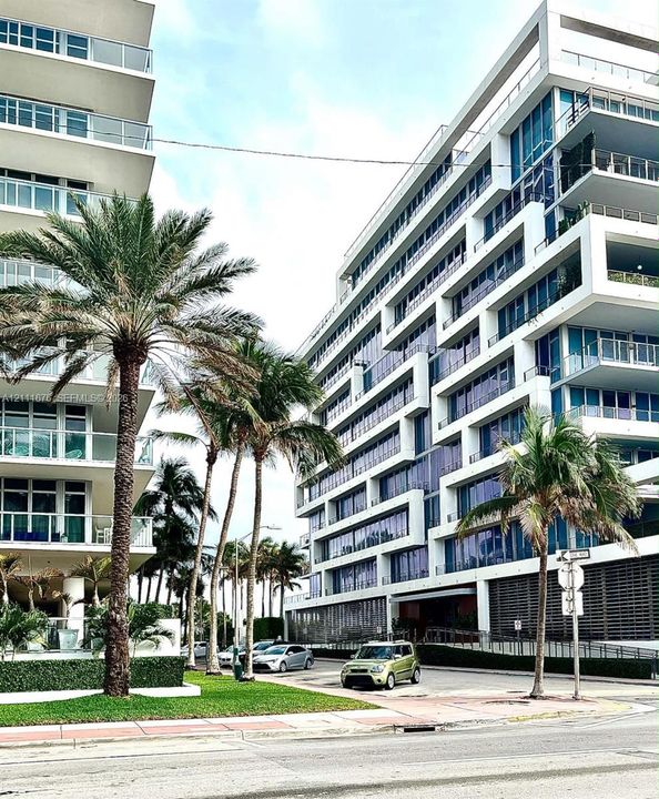 Contemporary mid-rise building exterior featuring geometric white concrete framing, expansive floor-to-ceiling glass paneling, and private recessed balconies