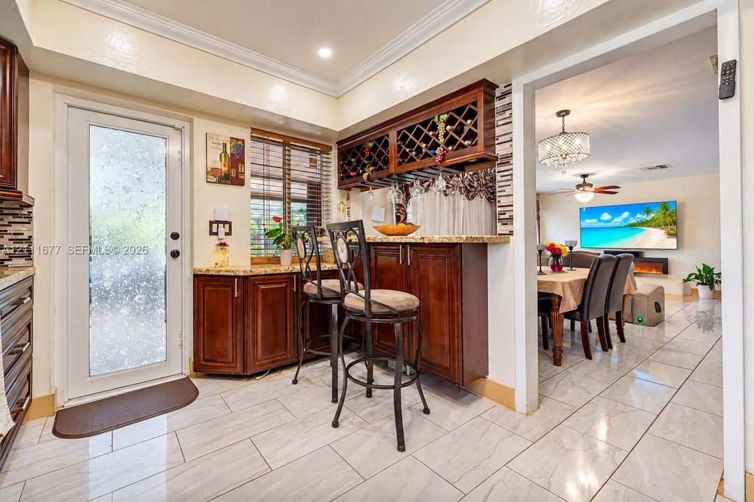 Kitchen featuring wood cabinetry with built-in wine rack, stone countertops, tiled flooring, and a glass-paneled exterior door