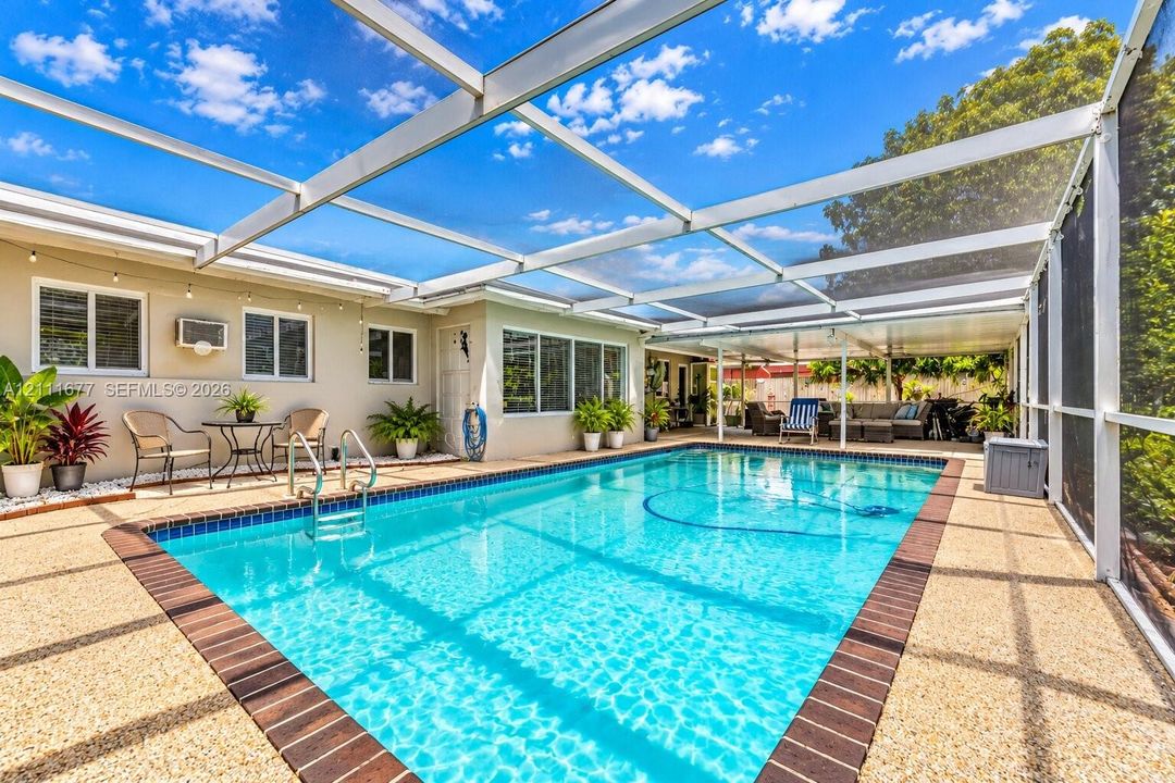 Screened lanai featuring a swimming pool with dark-toned tile coping, a pebbled pool deck, and a metal-framed enclosure