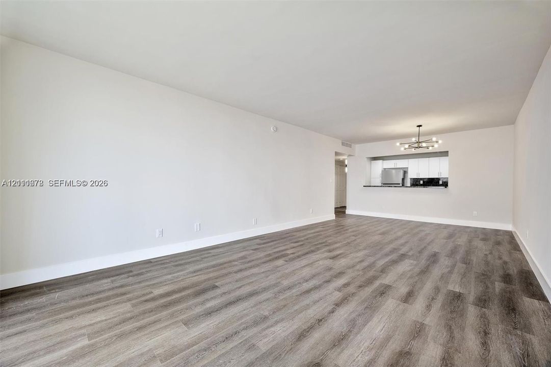 Living space featuring wood-finish flooring, recessed ceiling lighting, and a kitchen pass-through window with an integrated breakfast bar