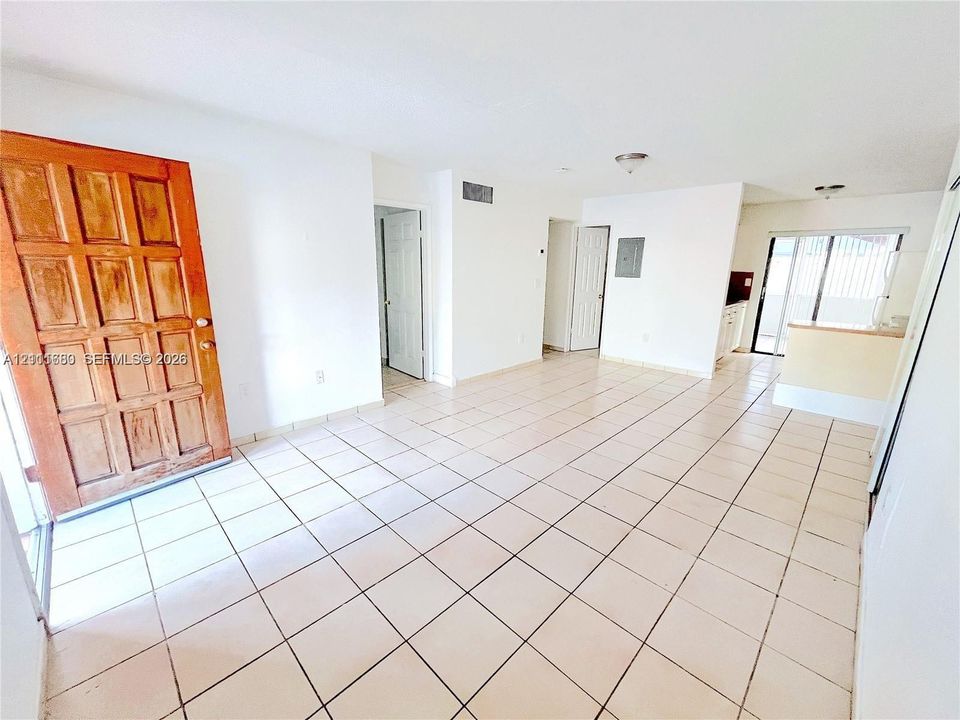 Interior space featuring neutral tile flooring, a six-panel natural wood entry door, and sliding glass patio doors