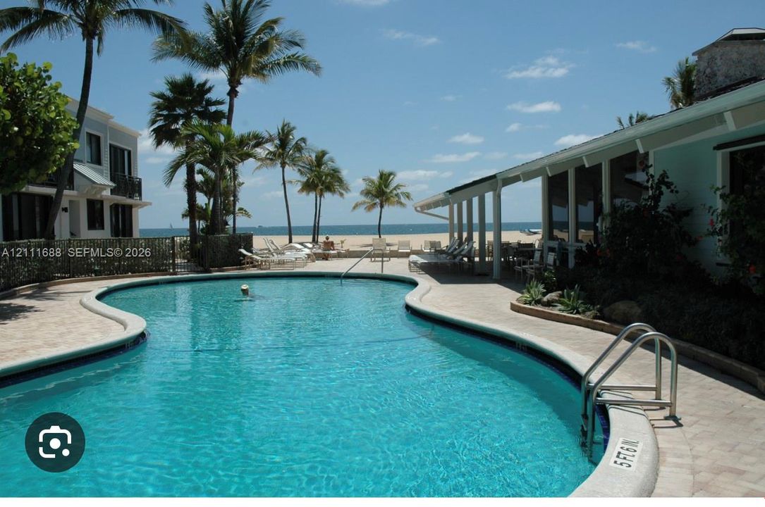Curvilinear swimming pool with stone paver decking, sheltered patio, and oceanfront placement