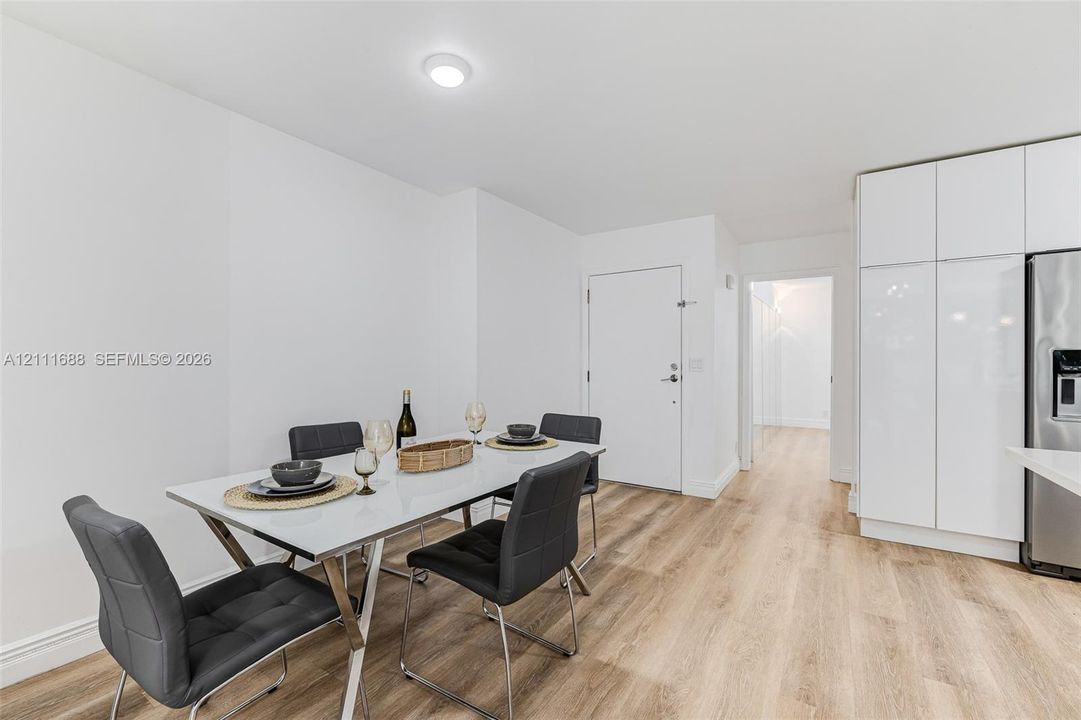 Modern interior space featuring wood-finish flooring, high-gloss white cabinetry, and flush-mount ceiling lighting