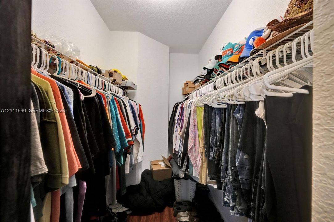 Walk-in closet featuring dual levels of white wire shelving and wood-finish flooring