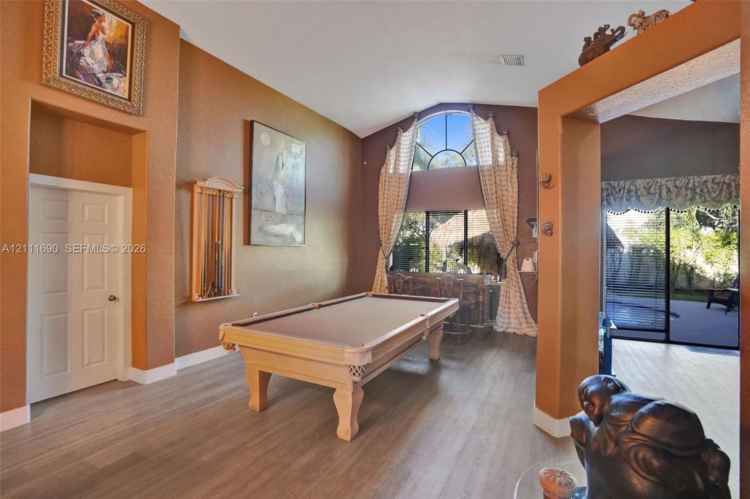 Vaulted ceilings, arched transom window, wood-finish flooring, and sliding glass patio door