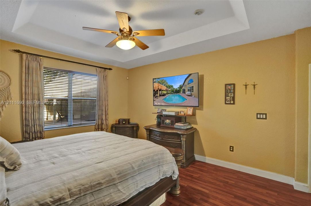 Tray ceiling, wood-finish flooring, and ceiling fan with integrated lighting