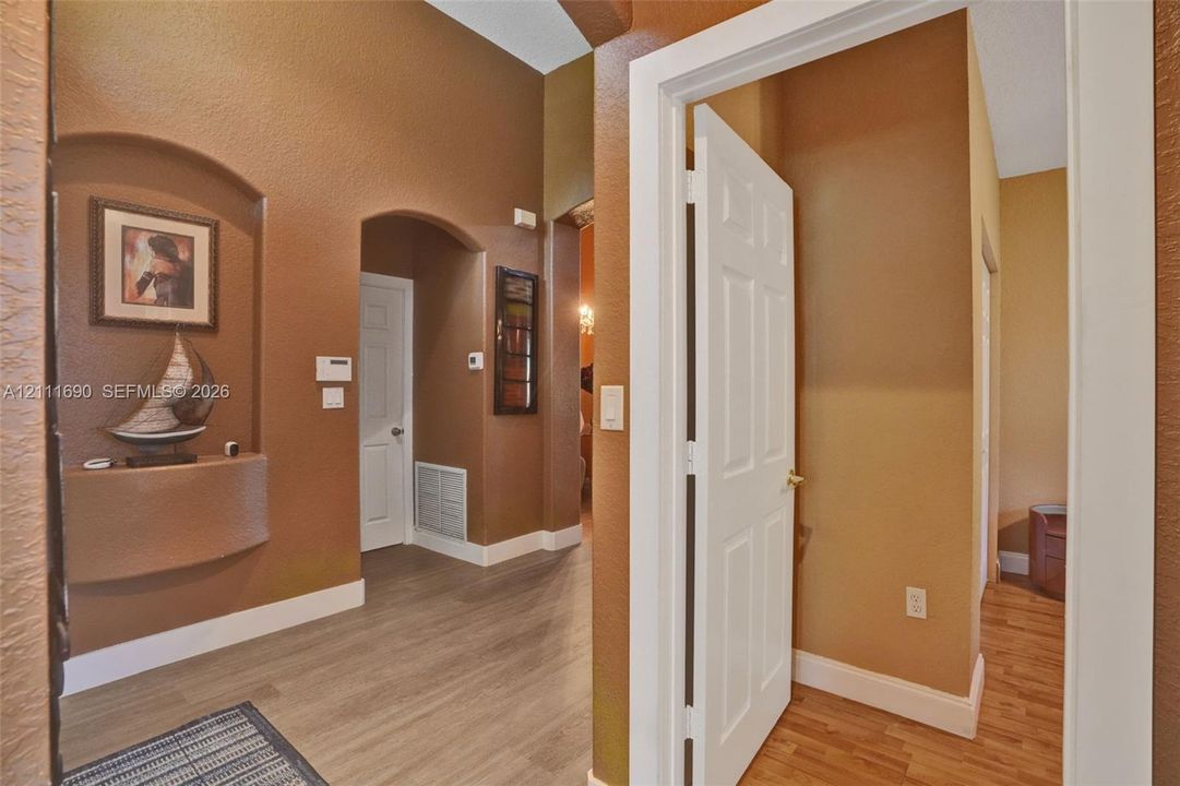 Entryway featuring vaulted ceilings, arched wall niches, multi-panel doors, and wood-finish flooring