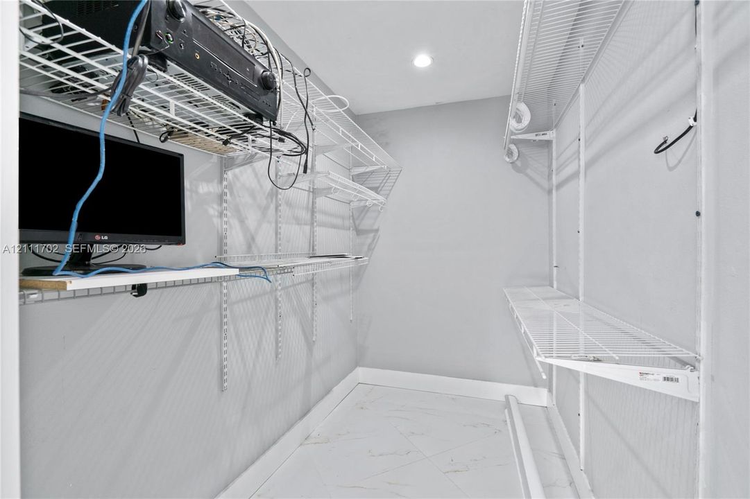 Storage space featuring wall-mounted wire shelving units and tile flooring