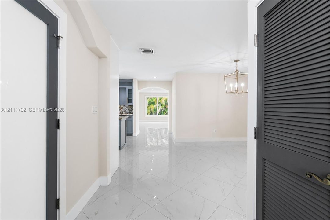 Interior featuring polished tile flooring with a marble-patterned finish, dark gray louvered closet doors, and a geometric metal pendant light fixture