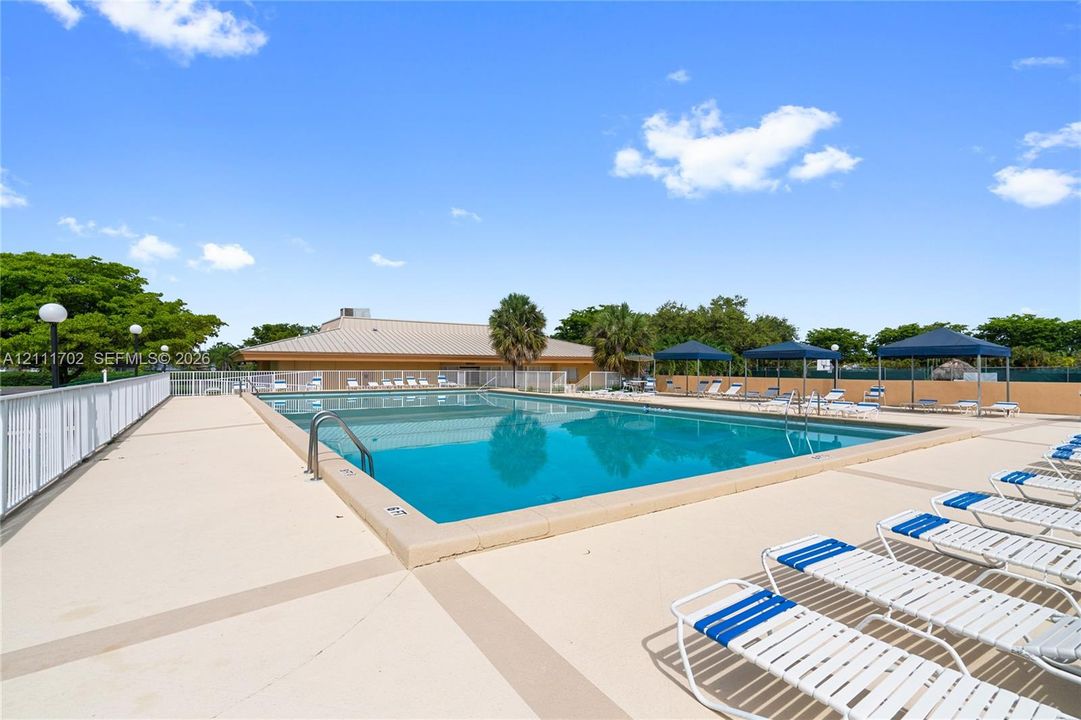 Rectangular swimming pool with metal ladder entry, concrete deck, and perimeter safety fencing