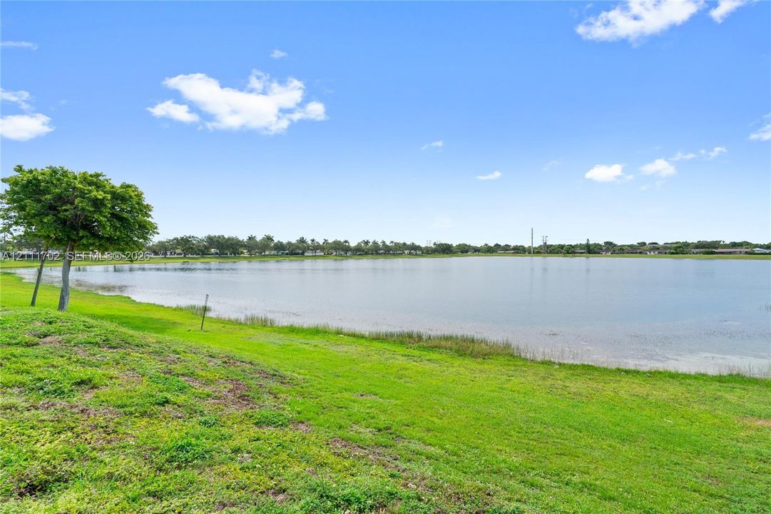 Waterfront lot featuring a large body of water, expansive grassy grounds, and mature trees