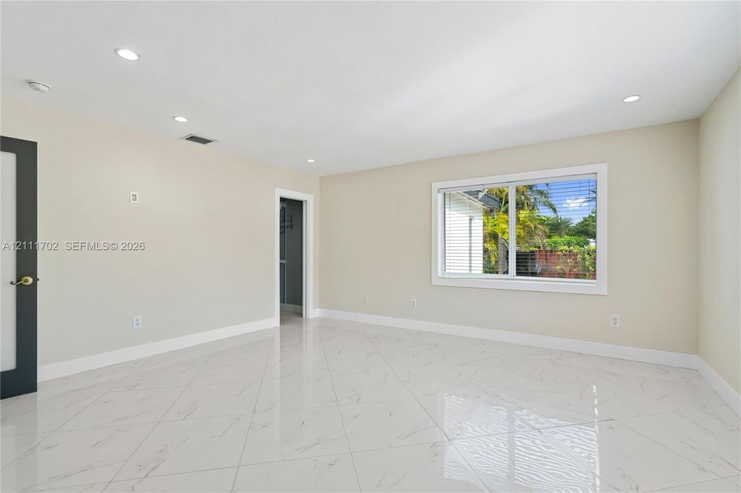Light-filled room featuring large-format tile flooring with marble-finish veining, crisp neutral wall paint, recessed lighting, and a single-pane horizontal window