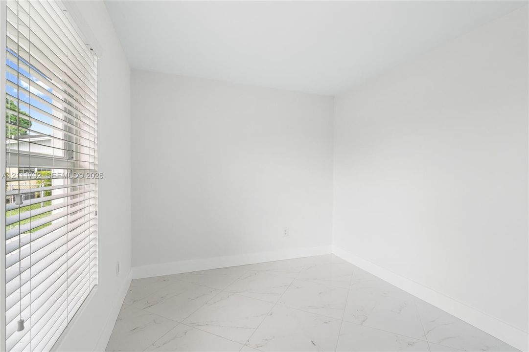 Neutral-toned room featuring large-format tile flooring and horizontal window blinds
