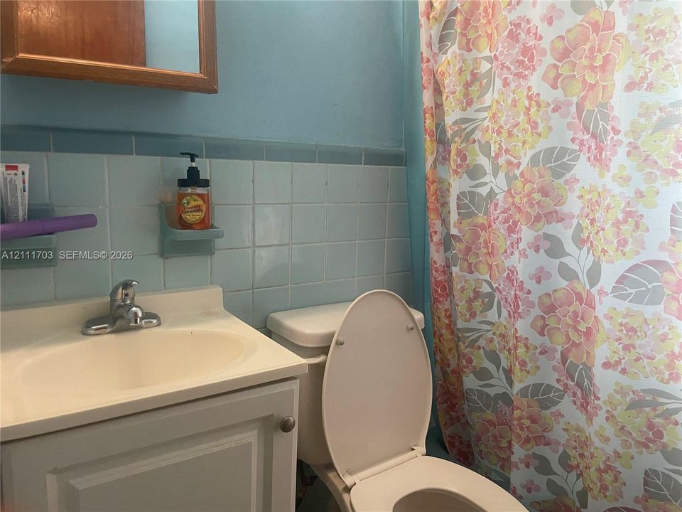 Bathroom featuring a vanity with an integrated sink and chrome faucet, light blue ceramic wall tiling, and a built-in recessed soap dish