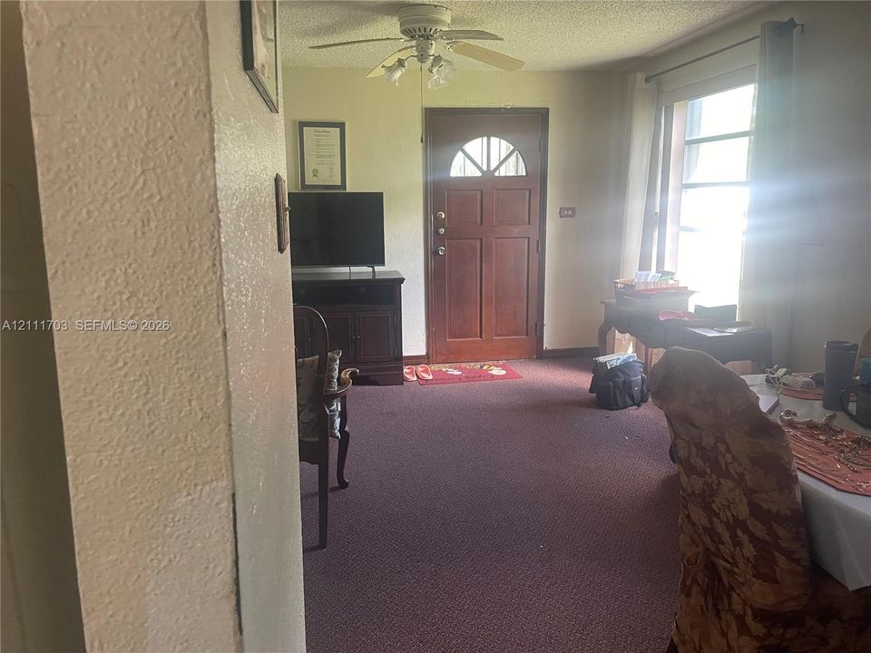 Entry area featuring a solid wood door with a semi-circular glass insert, multi-pane window, and a ceiling-mounted light fixture with a fan