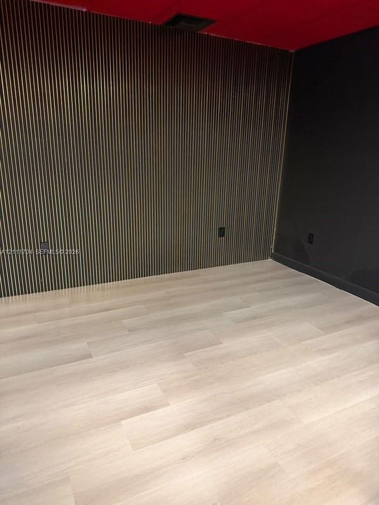 Interior featuring a wood-slat accent wall, high-contrast matte wall finishes, and light-toned wood-finish flooring