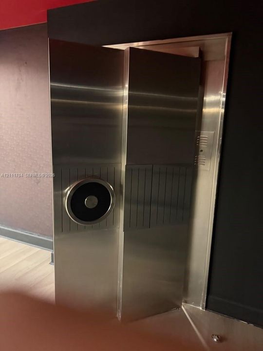 Stainless steel elevator doors featuring a metallic finish and a circular control panel