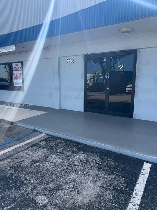 Commercial exterior featuring double glass entry doors, concrete entry pad, and metal-paneled facade