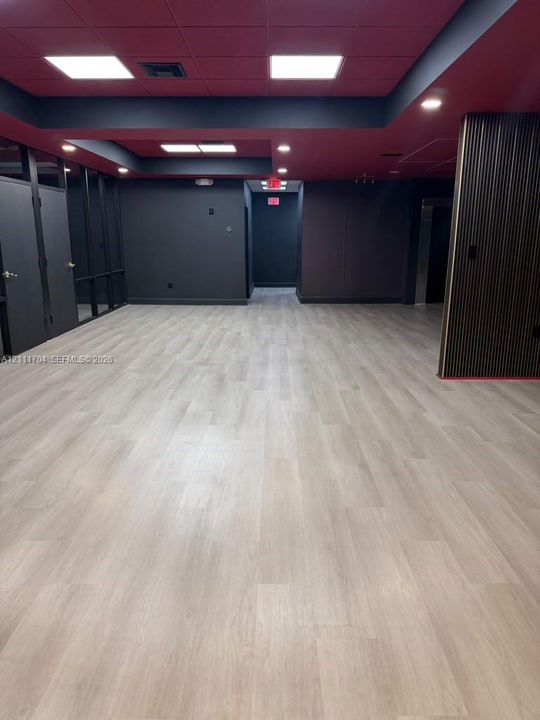 Open floor plan featuring wood-finish flooring, recessed lighting, matte black wall accents, and vertical wood slat detailing