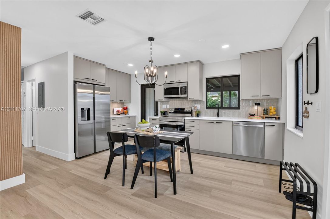 Kitchen featuring flat-panel cabinetry, stainless steel appliances, wood-finish flooring, recessed lighting, and a chandelier fixture