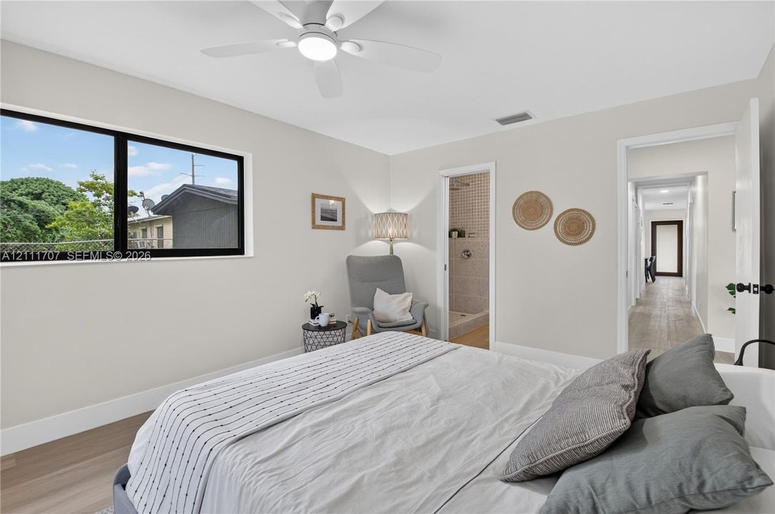 Neutral-toned interior featuring wood-finish flooring, a contemporary ceiling fan with integrated lighting, and large, black-framed picture windows