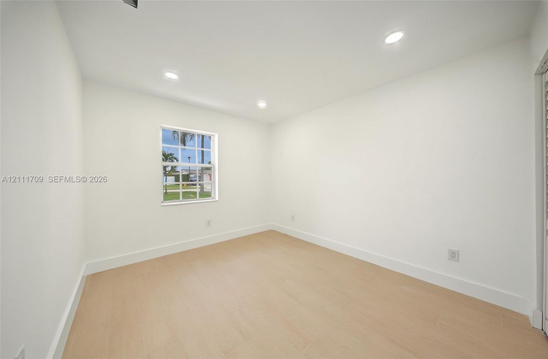 Neutral interior space featuring recessed ceiling lighting, light-toned wood-finish flooring, and a single-hung window with a muntin grid