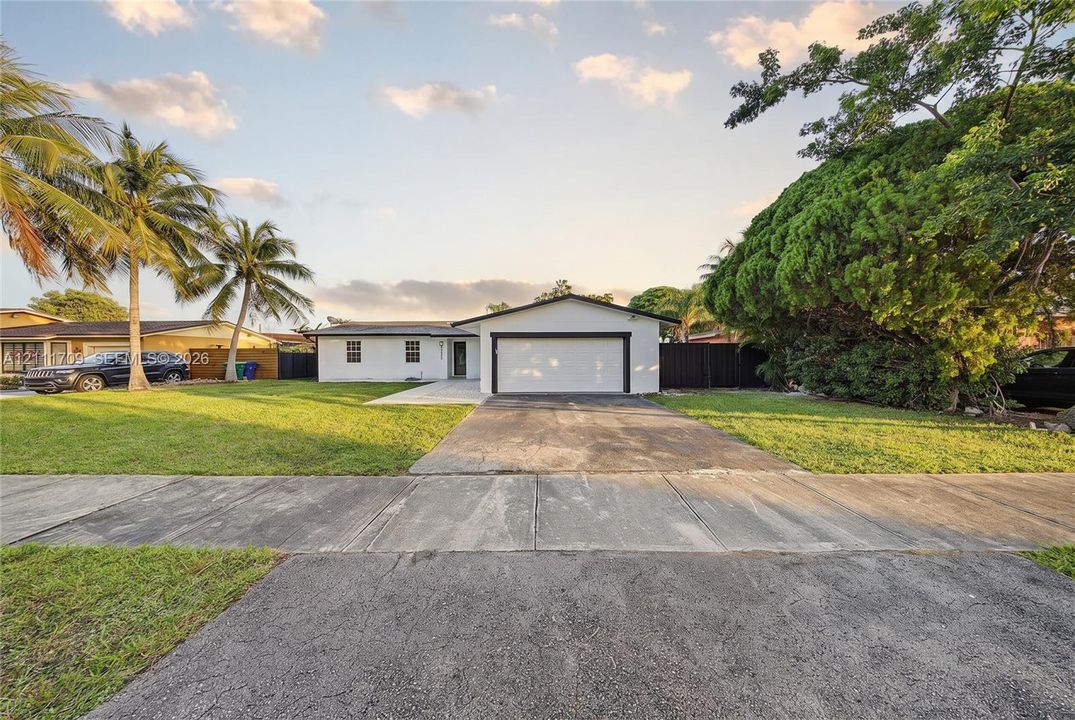 Single-story residence featuring a front-facing attached garage, concrete driveway, and expansive lawn
