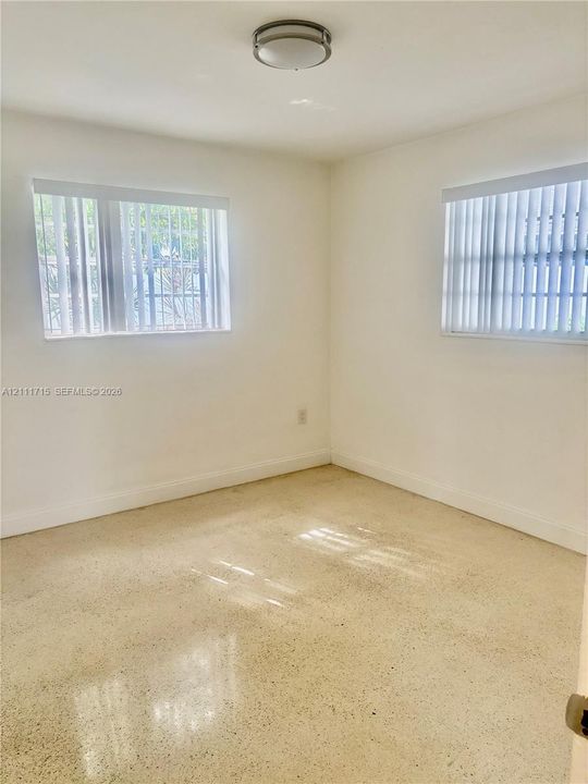 Interior room featuring polished concrete flooring, neutral wall finishes, dual windows with vertical blinds, and a ceiling-mounted light fixture