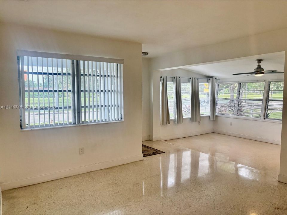 Polished terrazzo flooring, expansive multi-pane windows, and a ceiling fan with integrated lighting