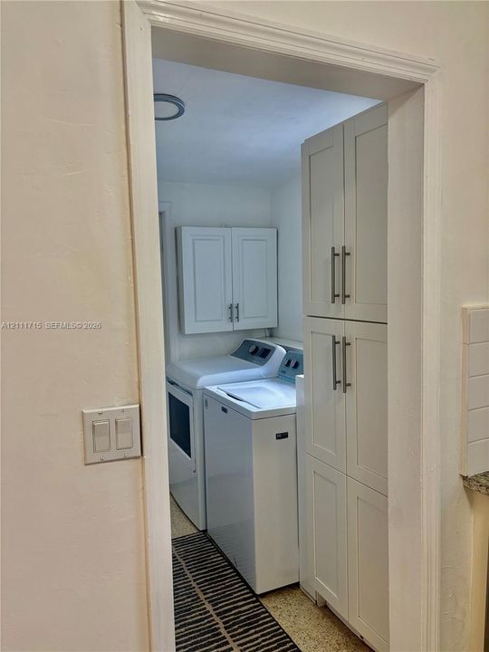 Laundry area featuring white shaker-style cabinetry, tall built-in pantry storage, and brushed nickel hardware