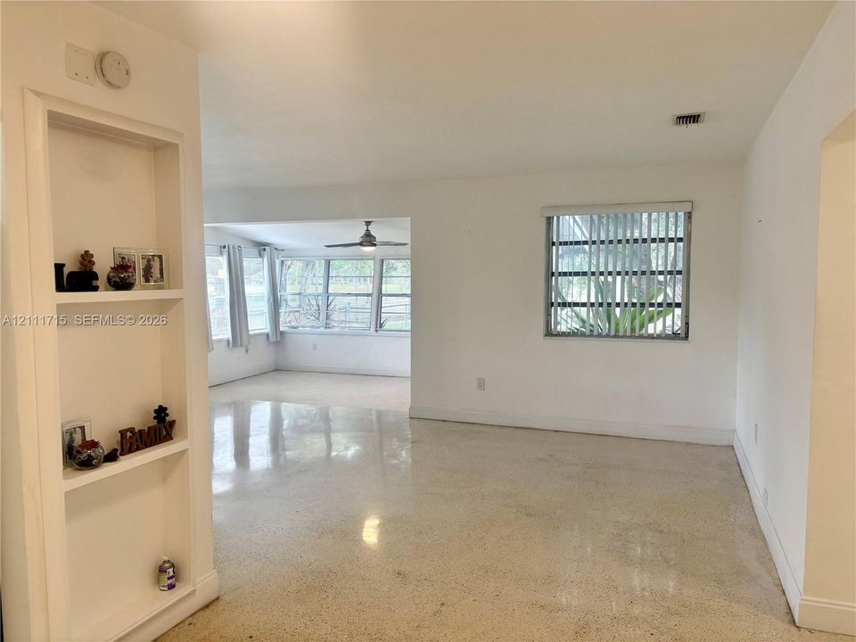 Interior featuring polished terrazzo flooring, built-in recessed shelving, and large windows with horizontal blinds