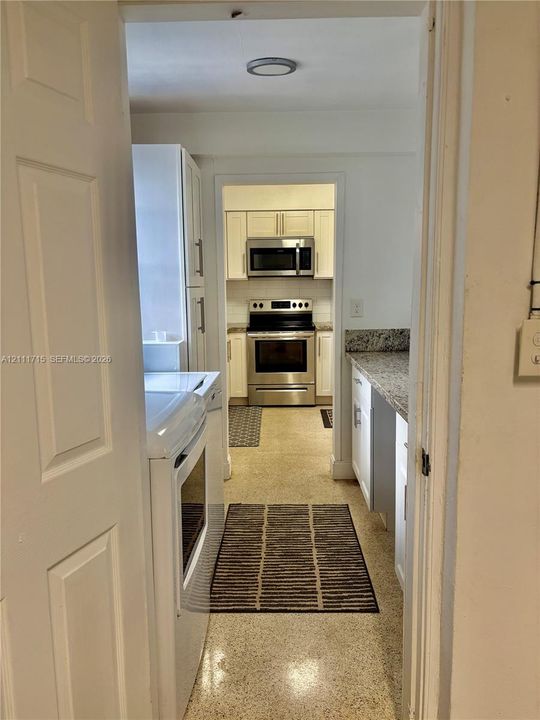 Kitchen featuring white cabinetry, stone-finish countertops, and a stainless steel oven and microwave