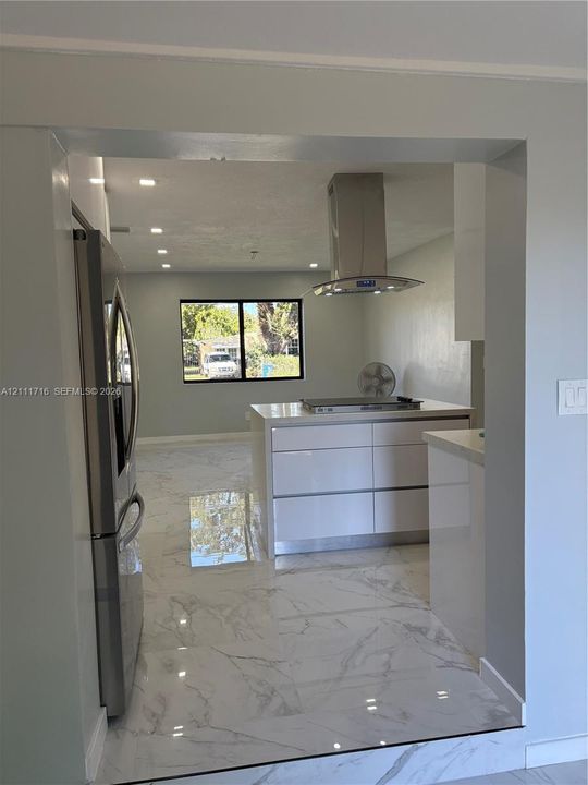 Kitchen featuring large-format tile flooring, a central island with a built-in cooktop, stainless steel ventilation hood, and recessed lighting