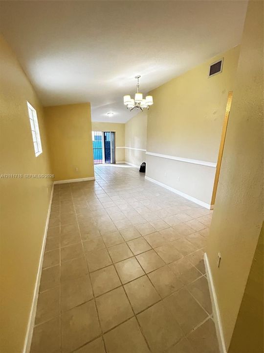 Interior space featuring ceramic tile flooring, vaulted ceilings, chair rail molding, and a five-light chandelier
