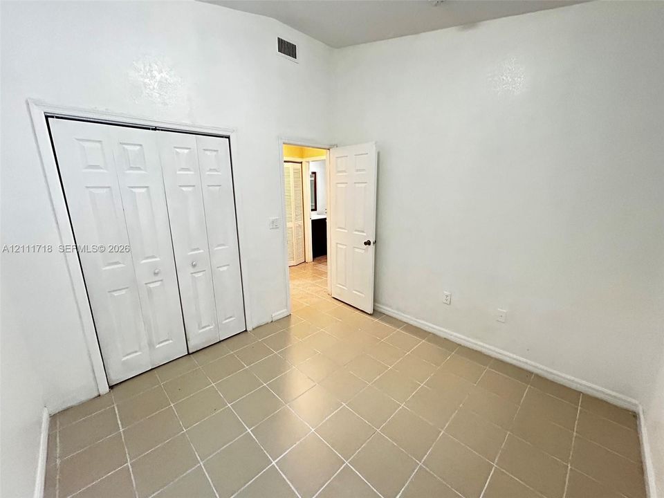 Neutral interior featuring high ceilings, neutral tile flooring, and a large reach-in closet with six-panel bi-fold doors