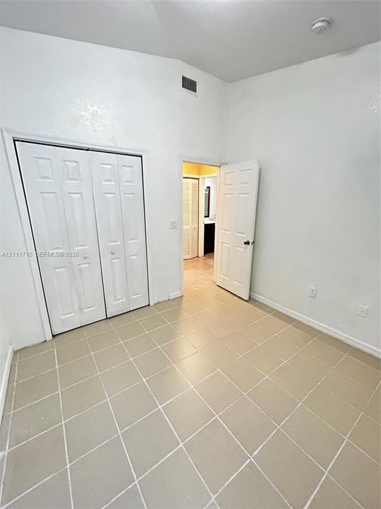 Neutral-toned tile flooring, high ceilings, white bi-fold closet doors, and interior paneled doors