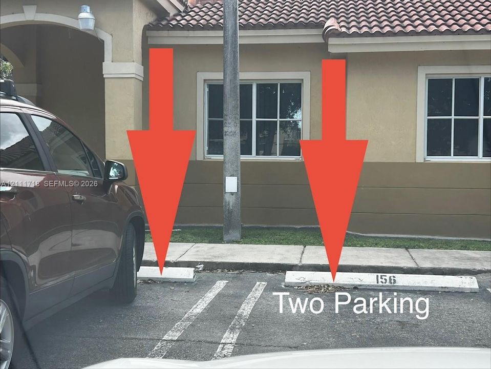 Designated exterior parking area featuring two assigned spaces with concrete wheel stops