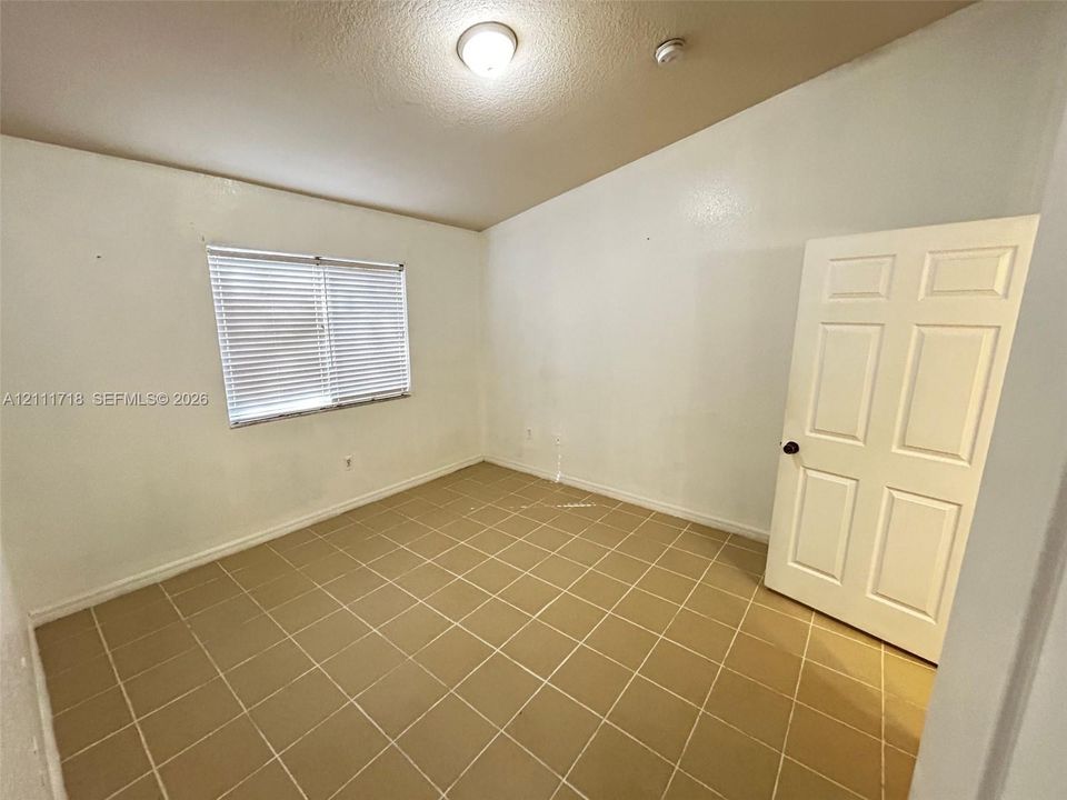 Room featuring vaulted ceilings, ceramic tile flooring, and a six-panel interior door