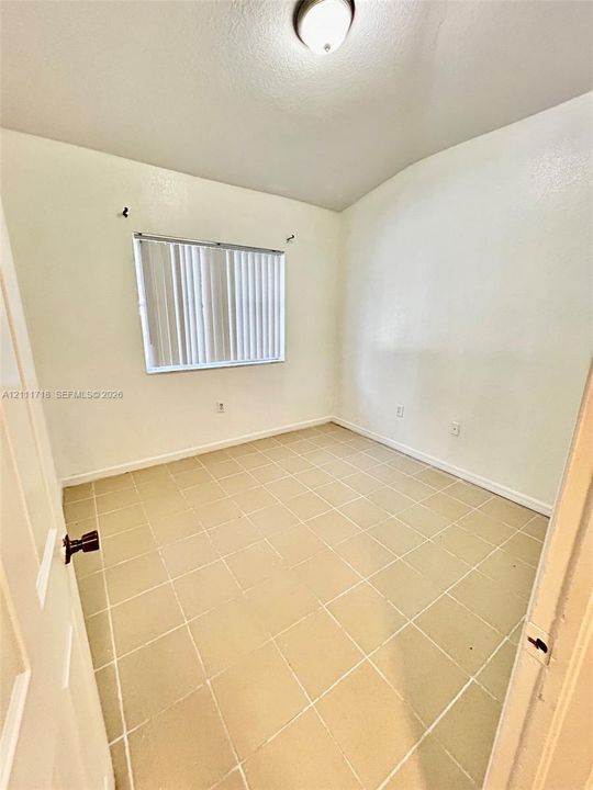 Neutral-toned tile flooring, white wall finish, window with integrated vertical blinds, and ceiling-mounted dome lighting