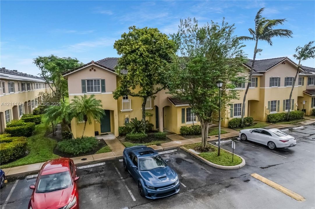 Stucco exterior featuring tile roofing, shuttered windows, and manicured landscaping