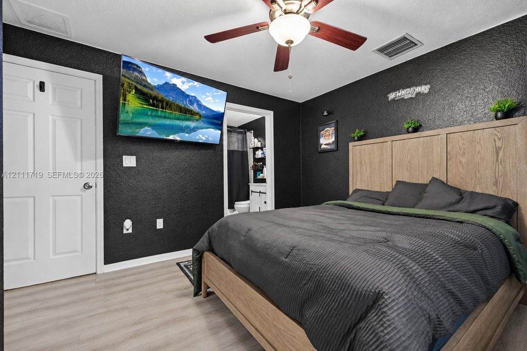Textured charcoal-painted walls, light wood-finish flooring, and a ceiling fan with integrated lighting