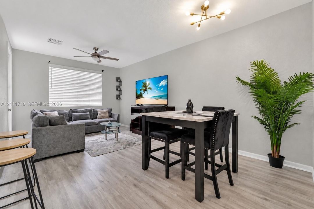 Neutral interior space featuring wood-finish flooring, a modern sputnik-style ceiling light fixture, and a ceiling fan