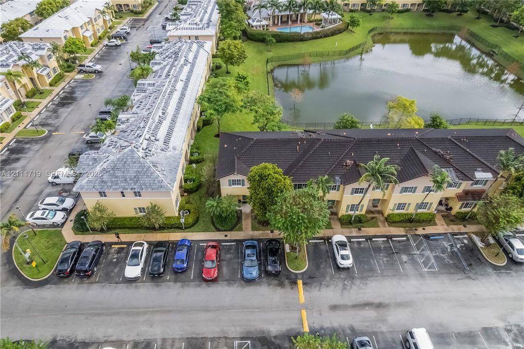 Aerial perspective of multi-unit residential buildings featuring dark-toned tile roofing, exterior stucco finishes, and dedicated surface parking