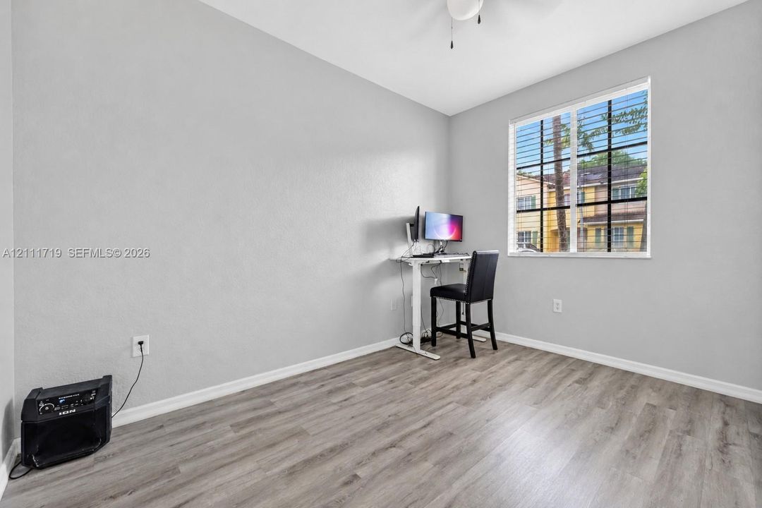Room featuring neutral-toned walls, wood-finish flooring, a multi-pane window with a grid pattern, and a ceiling-mounted light fixture