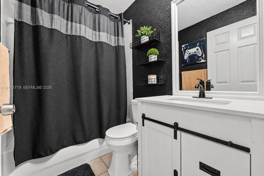 White vanity with sliding barn door detailing, matte black hardware, rectangular sink, and framed mirror